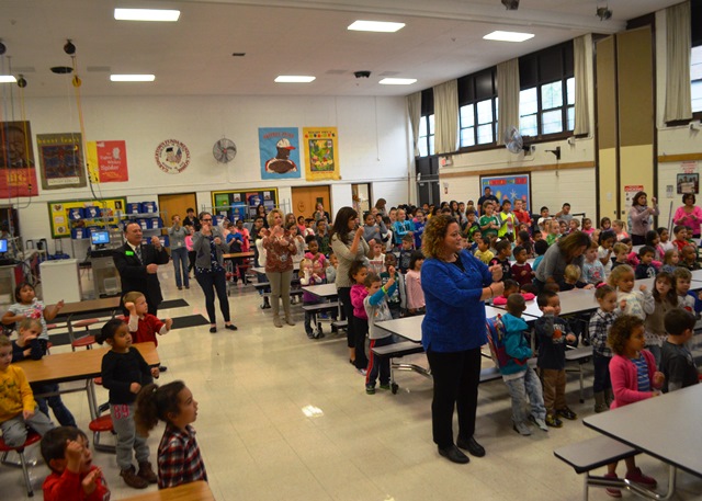 Cafeteria full of students watching assembly