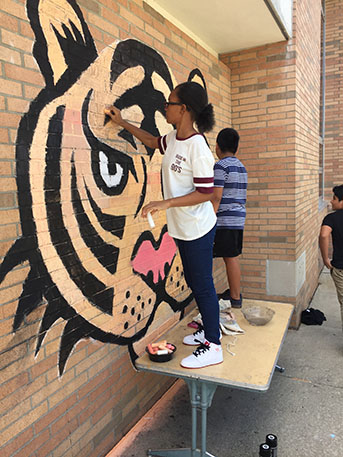A student painting the lion mural